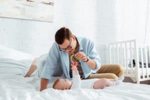 Single young father on the bed admiring his baby.