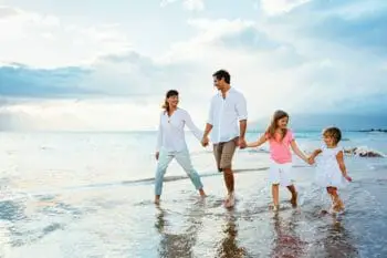 Young family walking along the ocean getting their feet wet.