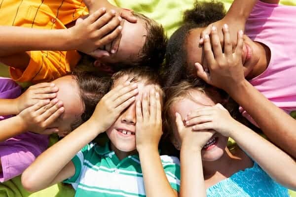 Children covering their eyes and smiling.