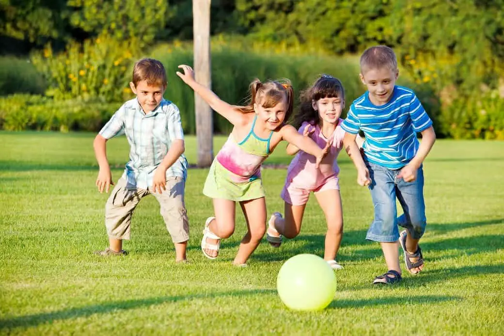 Children outside kicking a ball.