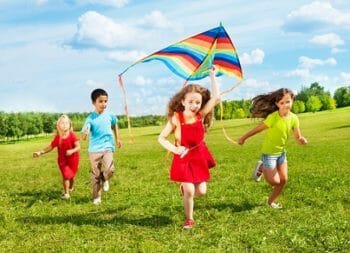 Young children running with a kite.