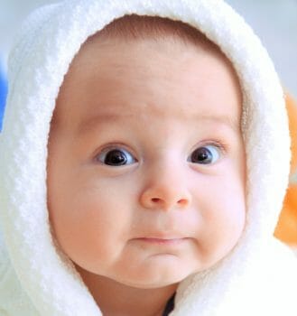 Baby with a funny look on its face wearing a hoody.