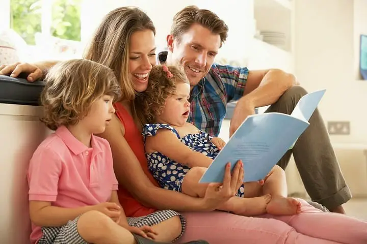 Young family sitting on the couch and reading a book.