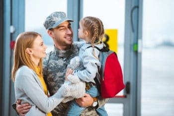 Military dad with wife holding his small daughter.