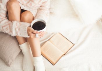 A women relaxing with a book and a warm drink