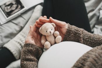 Pregnant mom holding a small teddy bear.